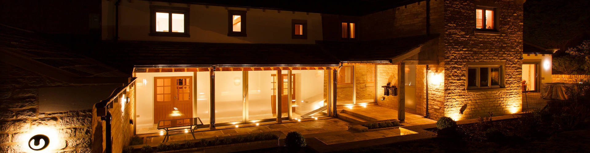 Title Image: A warmly-lit glass hallway linking two ends of a converted Yorkshire farmhouse.