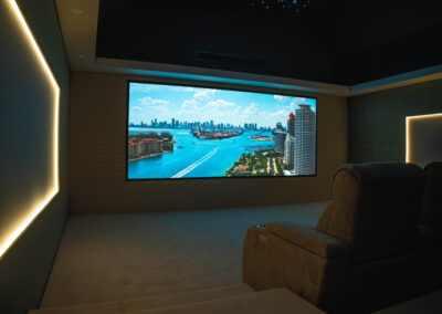 Luxury home cinema in Wynyard Park featuring a large projection screen, tiered seating and ambient wall lighting