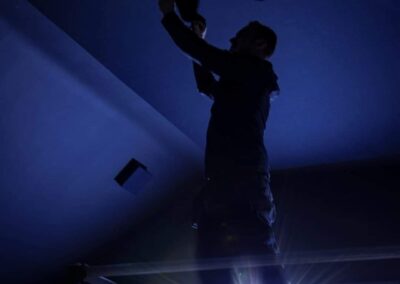 Silhouette of an installer fitting fibre-optic star ceiling lighting in the Wynyard Park home cinema.